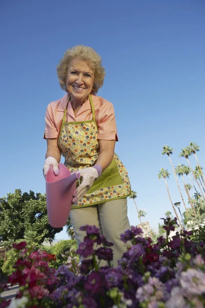Heureux senior femme arrosage plantes — Photo