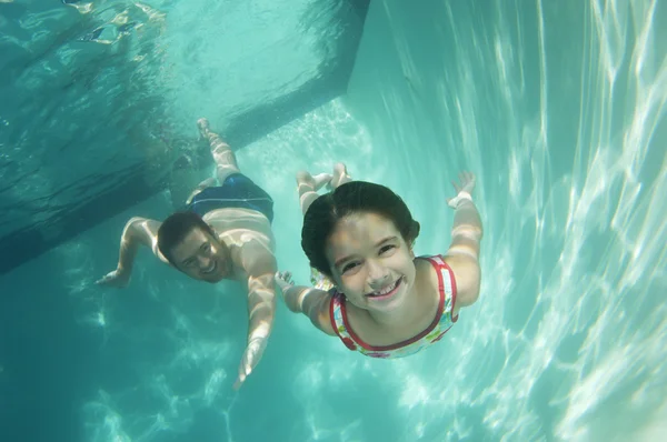 Отец и дочь плавают под водой — стоковое фото