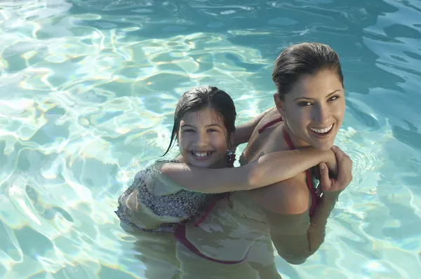 Moeder dochter geven piggy terug in zwembad — Stockfoto