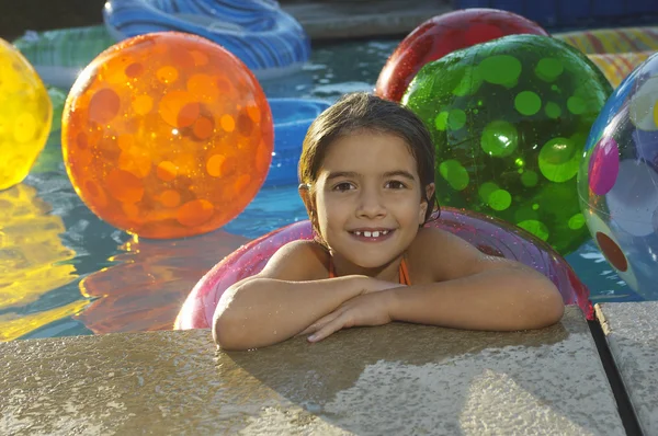 Meisje met drijvende ring en strand ballen in zwembad — Stockfoto