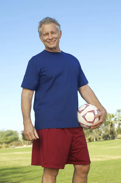 Starší muž drží fotbalový míč v parku — Stock fotografie