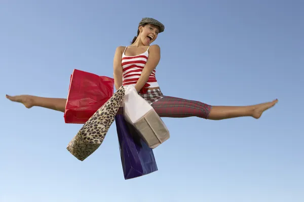 Jovem mulher pulando com sacos de compras — Fotografia de Stock