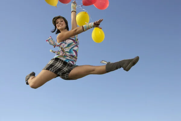 Mujer haciendo divisiones en aire sosteniendo globos — Foto de Stock