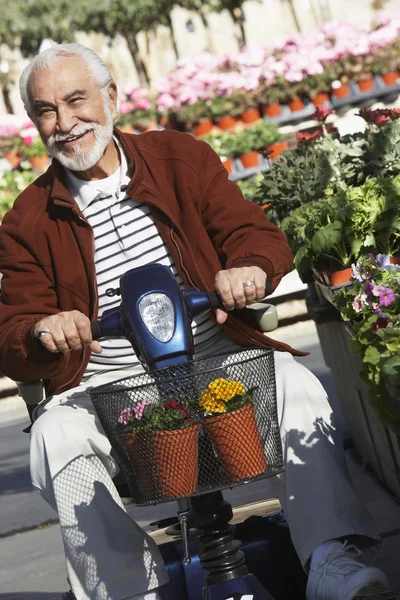 Senior man op motor scooter op tuin — Stockfoto