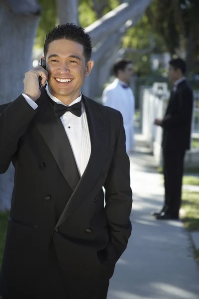 Guapo joven en esmoquin usando teléfono celular en Quinceañera —  Fotos de Stock