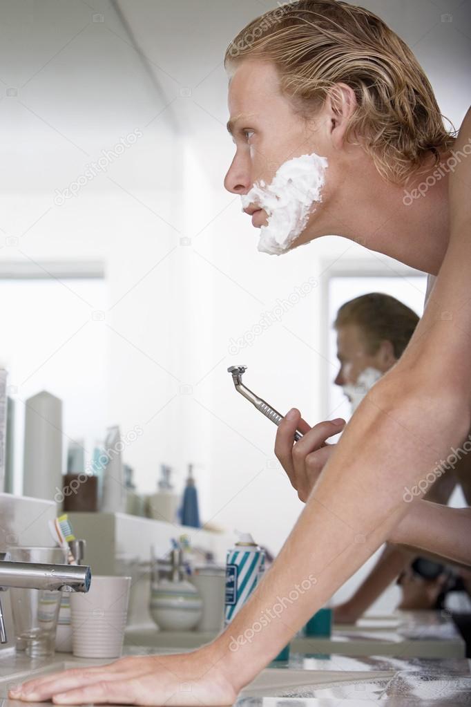 Young Man Shaving In Bathroom