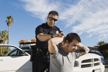 Police Officer Arresting Young Man clipart