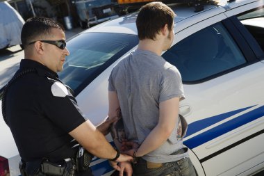 Police Officer Arresting Young Man clipart