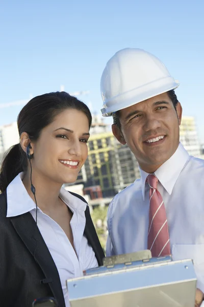 Businessman Showing Clipboard To Businesswoman With Earpiece — Stock Photo, Image