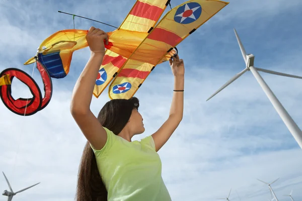 Mädchen hält Flugzeugdrachen an Windpark — Stockfoto