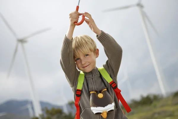 Мальчик держит зонтик на ветряной ферме — стоковое фото