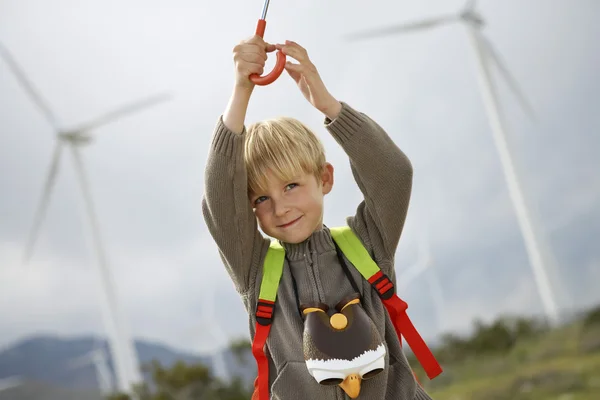 Ragazzo che tiene l'ombrello al parco eolico — Foto Stock