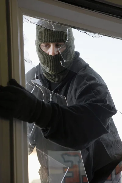 Maskierter Dieb bricht durch Fenster ein — Stockfoto