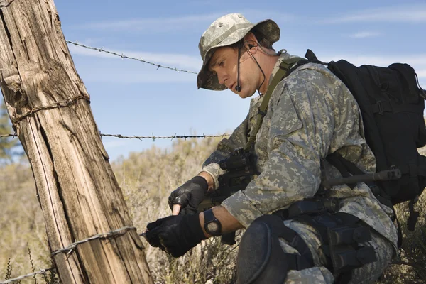 Voják stříhání ostnatého drátu plot — Stock fotografie