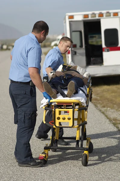 Paramédicos carregando vítima em maca — Fotografia de Stock