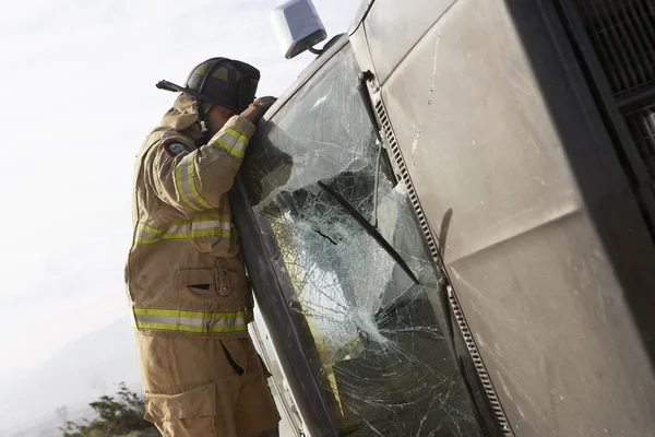 Tűzoltó vizsgálja a lezuhant autó — Stock Fotó
