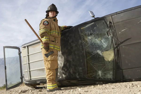 Tűzoltó állandó összetört autóval — Stock Fotó