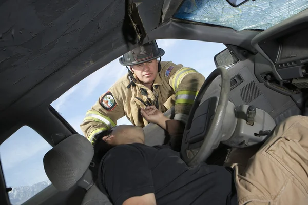 Feuerwehrmann schaut in verunglücktes Auto — Stockfoto