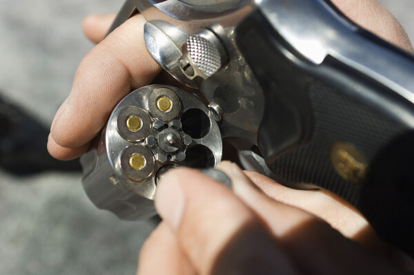 Man 's Hands Loading Bullets into Gun

