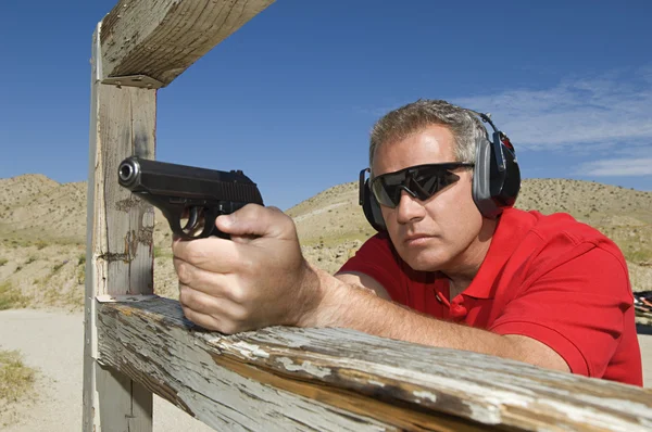 Hombre apuntando pistola de mano en el campo de tiro — Foto de Stock