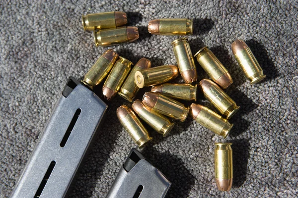Pistola revista y balas en la alfombra — Foto de Stock