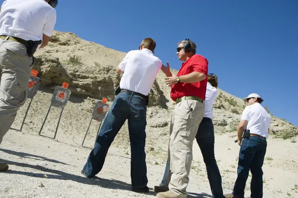 Instructor Assisting Aiming Guns At Firing Range — Stock Photo, Image