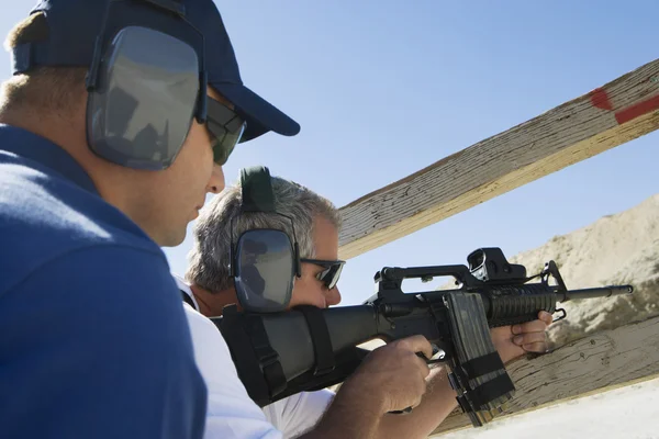 Instructor con hombre apuntando ametralladora — Foto de Stock