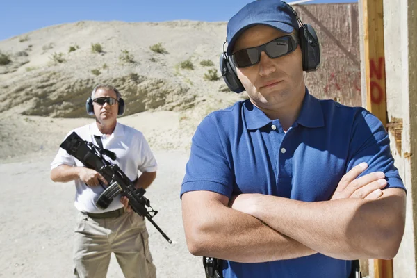 Twee mannen op het afvuren bereik in woestijn — Stockfoto