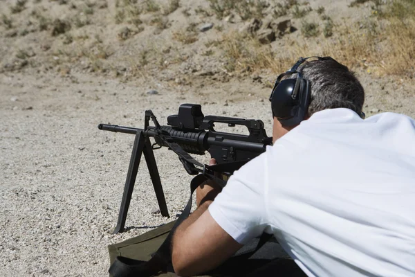 Uomo che punta mitragliatrice al poligono di tiro — Foto Stock