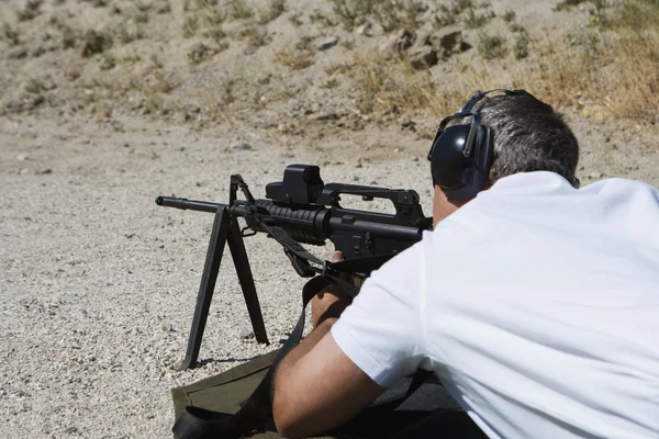 Hombre apuntando ametralladora en campo de tiro — Foto de Stock