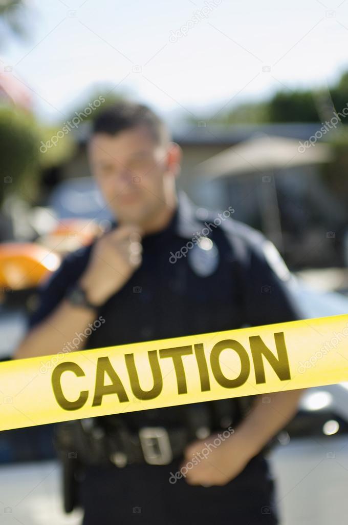 Police Officer Standing Behind Caution Tape