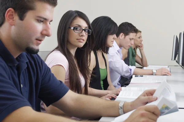 Kvinnlig student med klasskamrater i datorsal — Stockfoto