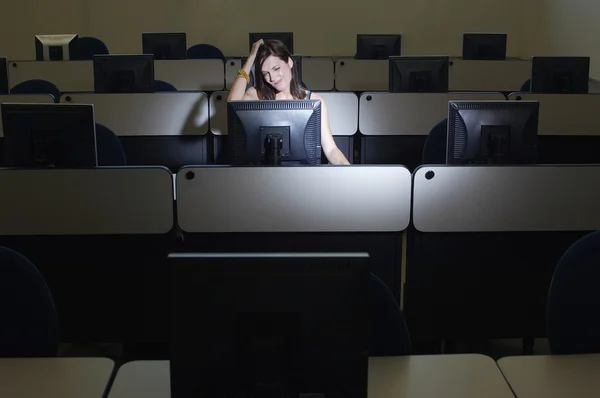 Studentin kratzt sich beim Blick auf Computer am Kopf — Stockfoto