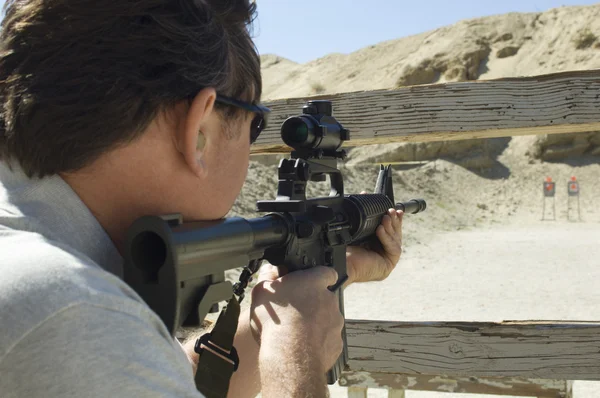 Un homme qui vise un fusil au champ de tir — Photo