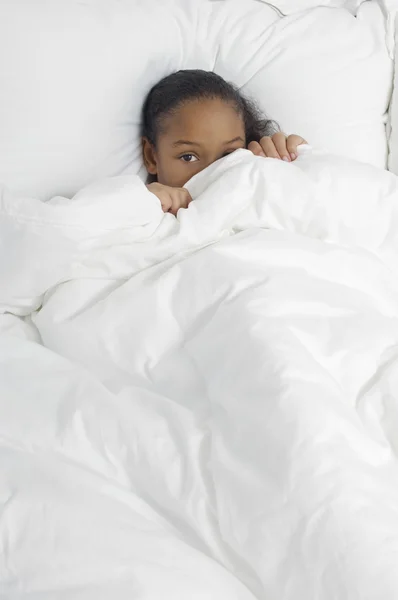 Застенчивая девушка прячется под одеялом — стоковое фото