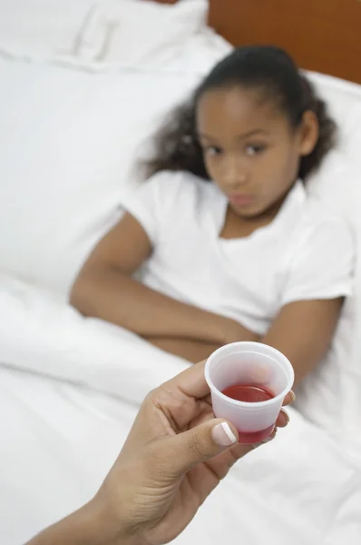 Ręka trzyma leki dla dziewczyny, leżąc w łóżku — Zdjęcie stockowe