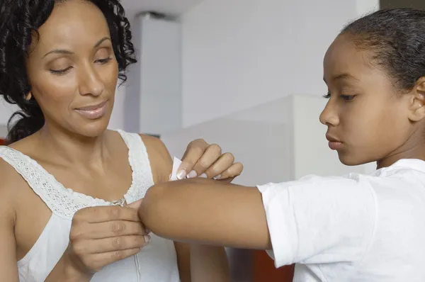 Madre aplicando vendaje en la mano de la hija — Foto de Stock