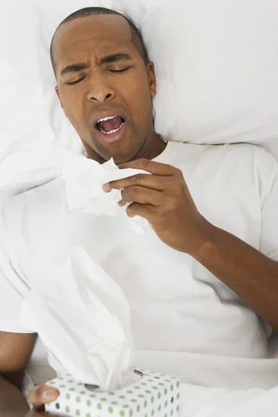 Hombre estornudando en la cama — Foto de Stock