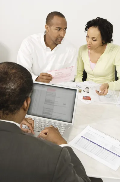 Conselheiro financeiro usando laptop com casal em discussão sobre documentos — Fotografia de Stock