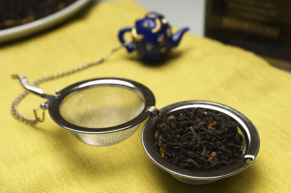 Hojas de té seco en colador en servilleta de mesa — Foto de Stock