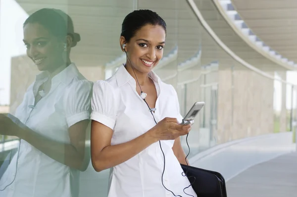 Zakenvrouw luisteren muziek op mobiele telefoon — Stockfoto