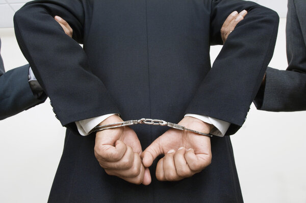 Бизнесмен в наручниках, а партнеры держат его за руки
