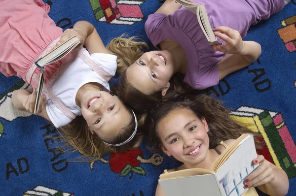 Friends Holding Books While Lying On Carpet — Stock Photo, Image