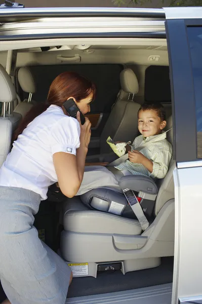 Donna d'affari utilizzando il telefono cellulare con figlio in auto — Foto Stock