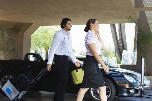 Pareja de negocios pasando por el coche — Foto de Stock