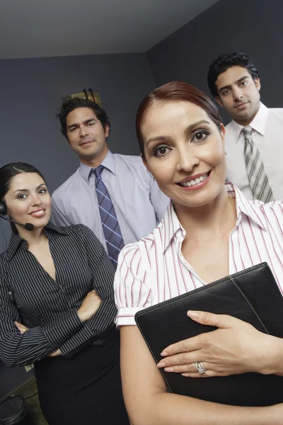 Бізнес-леді стоїть з колегами в офісі — стокове фото