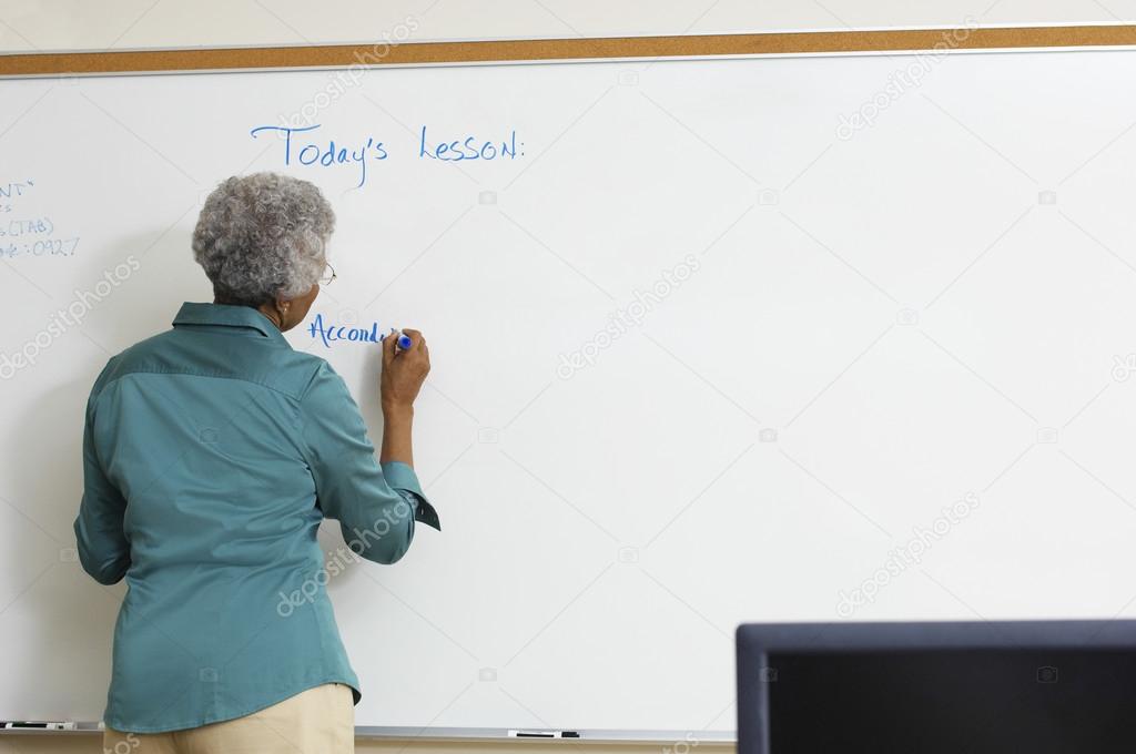 Senior Teacher Writing On Whiteboard
