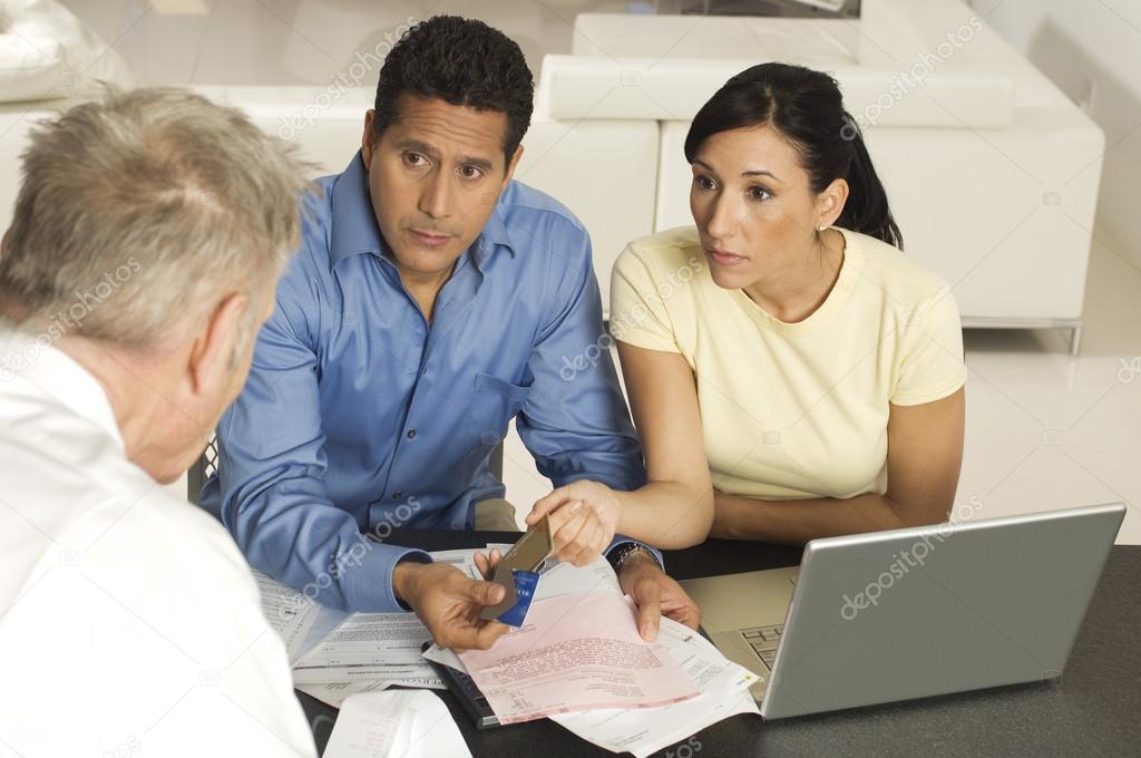 Couple Giving Documents And Credit Cards To Advisor