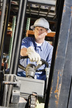 Adam forklift kullanıyor.