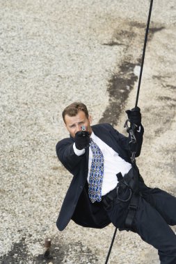 Male Spy Aiming Handgun While Rappelling clipart